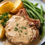 A serving spoon lifting a portion of creamy pork chops, potatoes, and green beans from the crockpot