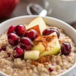 a bowl of warm cranberry apple crockpot oatmeal, topped with fresh cranberries