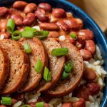 a hearty bowl of red beans and rice topped with slices of browned sausage