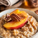 A comforting bowl of slow cooker peach cobbler oatmeal, topped with golden