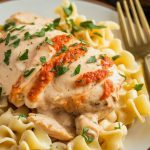 A cozy, close-up of Crockpot Angel Chicken served over a bed of buttery pasta