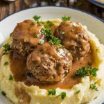 A final plated shot of Salisbury steak meatballs over creamy mashed potatoes