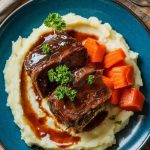 A beautifully plated dish of red wine-braised short ribs served over creamy mashed potatoes