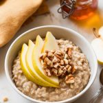 A bowl of freshly served spiced pear oatmeal topped with fresh pear slices