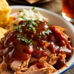 A close-up of juicy, tender shredded chicken smothered in BBQ sauce