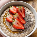 A creamy bowl of oatmeal topped with sliced strawberries