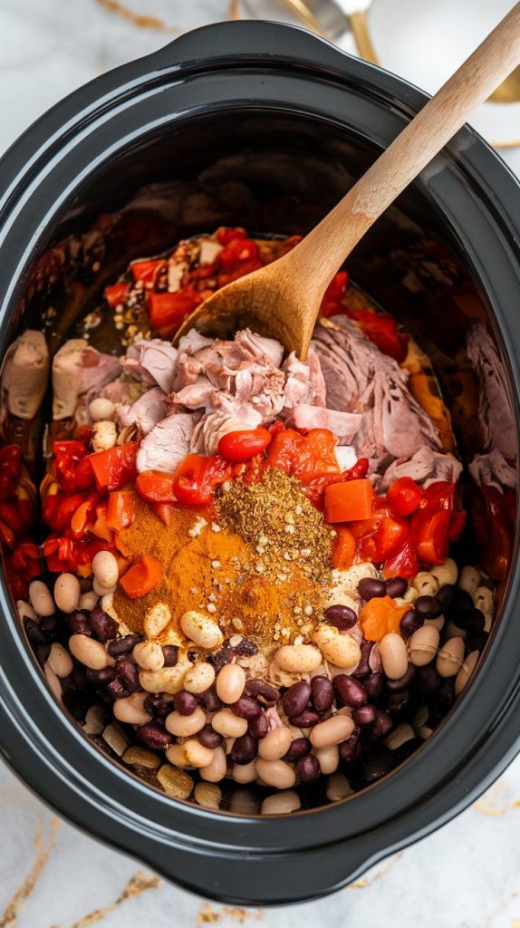 A crockpot filled with layered ingredients: browned turkey, beans, diced tomatoes, and spices