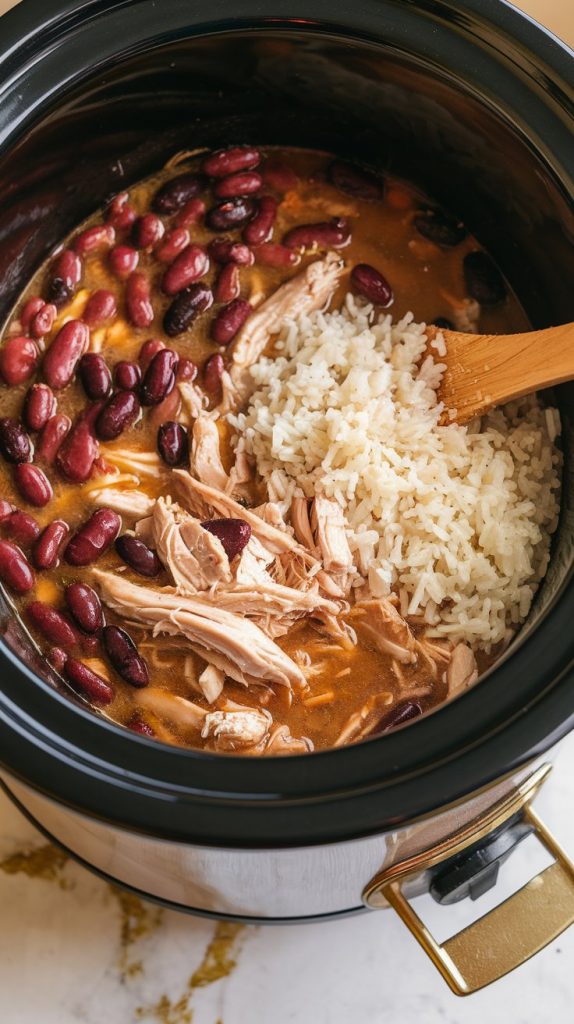 rice being stirred into the crockpot filled with chicken, beans, and broth