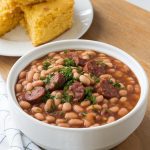 the finished crockpot pinto beans with sausage served in a white bowl