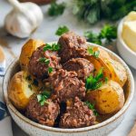 A serving of garlic butter beef bites and potatoes plated in a rustic white bowl