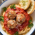 a serving of spaghetti topped with homemade meatballs and marinara sauce