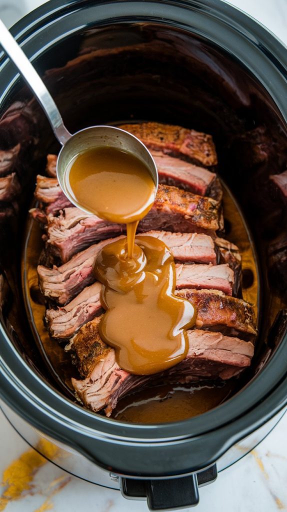 Short ribs layered in a crockpot with honey garlic sauce being poured over them