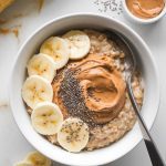 A serving of peanut butter and banana oatmeal in a white bowl