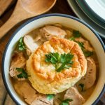 a bowl of chicken pot pie with a golden biscuit on top