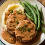 A plate of crockpot pork chops smothered in rich onion gravy