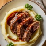 plated short ribs with mashed potatoes, drizzled with sauce and garnished with parsley