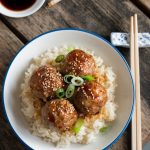 plated Asian-style meatballs garnished with sesame seeds and sliced green onions