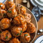 A serving platter filled with glossy, perfectly cooked orange marmalade meatballs