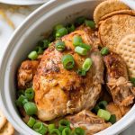 Crockpot crack chicken served in a white ceramic dish, garnished with fresh green onions