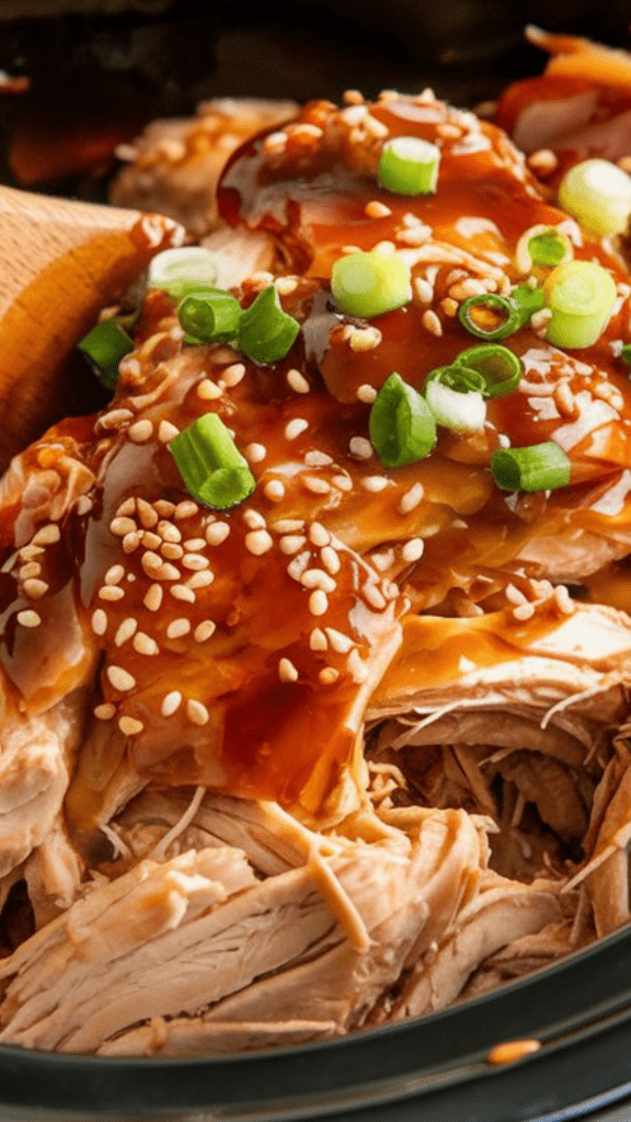 A slow cooker filled with shredded teriyaki chicken, glistening in a thick, glossy sauce