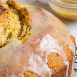 A freshly baked lemon poppy seed bread resting on a cooling rack, golden and slightly domed