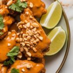 finished Thai peanut chicken wings on a plate, garnished with crushed peanuts and fresh cilantro