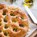 freshly baked focaccia bread resting on a wooden cutting board