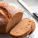 A freshly baked whole wheat honey bread loaf cooling on a wire rack, steam slightly rising