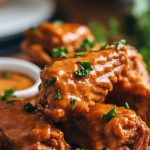 A plate of slow cooker honey mustard chicken wings, glistening with sticky sauce, garnished with fresh parsley