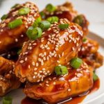 A plate of slow cooker teriyaki chicken wings, garnished with sesame seeds and green onions