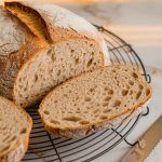 A freshly baked loaf of gluten-free bread cooling on a wire rack