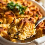 A warm, golden-brown slow cooker cornbread dressing in a white oval serving dish