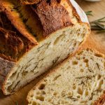 A freshly baked round loaf of rosemary olive oil bread, golden brown and crusty