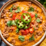 A bowl of hot, cheesy Velveeta queso dip, with tortilla chips arranged around it