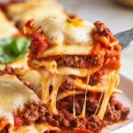 A plate of crockpot ravioli lasagna served hot, gooey cheese stretching with a fork