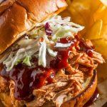 a pulled BBQ chicken sandwich on a toasted brioche bun, filled with tender, shredded chicken coated in a glossy