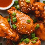 a serving platter with sticky, glistening orange chicken wings