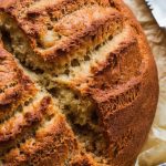 A freshly baked apple cinnamon bread loaf resting on parchment paper, with a golden brown crust