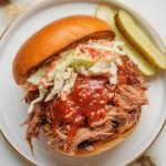 finished Coca-Cola pulled pork stacked high on a toasted brioche bun, glistening with sauce and topped with crunchy coleslaw