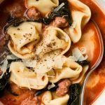 finished bowl of sausage tortellini soup, creamy broth glistening, parmesan melting on top, steam gently rising