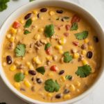a fully mixed cowboy queso dip served in a clean white ceramic bowl
