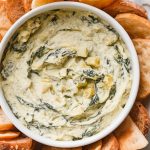 freshly scooped spinach artichoke dip served in a small round white bowl