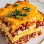 a serving of sausage breakfast casserole being scooped from the crockpot onto a white ceramic plate