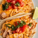 shredded queso chicken inside soft flour tortillas, chicken broken down into tiny, nearly minced strands, deeply seasoned with taco spices and cooked down in Rotel tomatoes