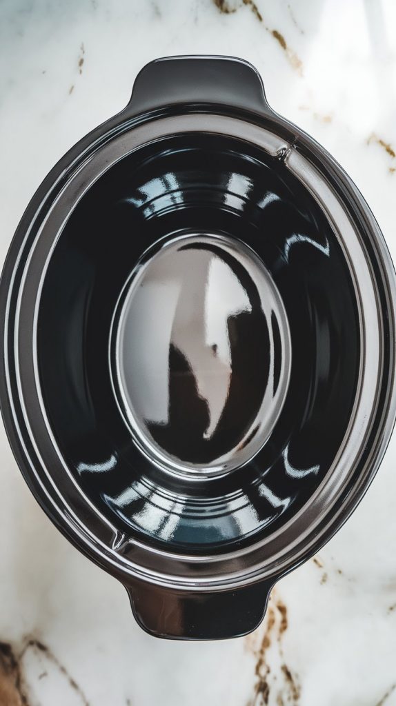 an empty black crockpot insert after being lightly sprayed with non-stick cooking spray