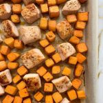 roasted chicken and sweet potatoes just out of the oven, fresh parsley sprinkled on top, steam rising, golden caramelized edges visible