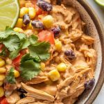creamy fiesta chicken served in a rustic ceramic bowl, with shredded chicken coated in creamy sauce, visible corn, black beans, and tomatoes